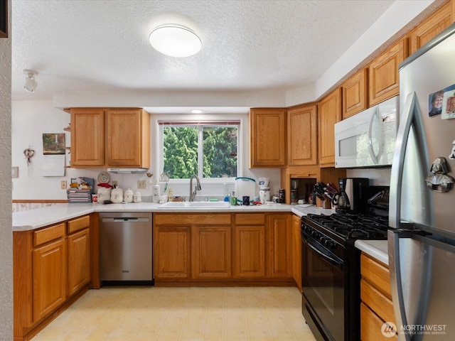 17417 29th Dr SE, Bothell, WA 98012 - kitchen featuring stainless steel appliances, a sink, light countertops, brown cabinetry, and a textured ceiling