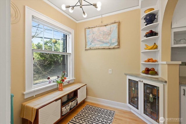detailed view of a chandelier, wood finished floors, ornamental molding, and baseboards