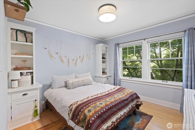 bedroom featuring light wood-type flooring, baseboards, and ornamental molding