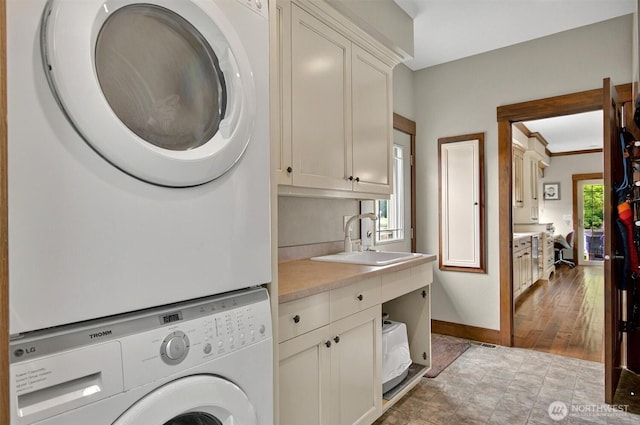 45 N Welcome Slough Rd, Cathlamet, WA 98612 - clothes washing area featuring stacked washing machine and dryer, cabinet space, and baseboards