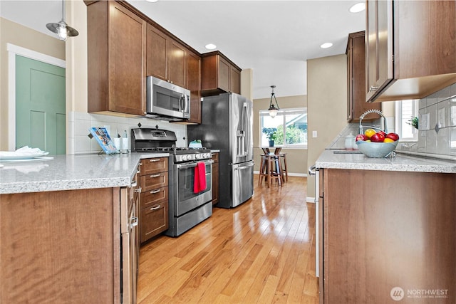 kitchen with stainless steel appliances, light wood-style flooring, backsplash, baseboards, and recessed lighting