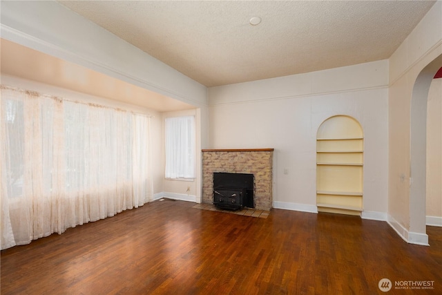 766 120th St S Unit A & B, Tacoma, WA 98444 - unfurnished living room featuring arched walkways, a wood stove, wood finished floors, baseboards, and built in features