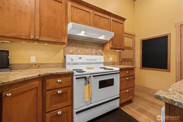 2677 Sumac Ln, Leavenworth, WA 98826 - kitchen featuring electric range, under cabinet range hood, brown cabinetry, light wood-type flooring, and light stone countertops