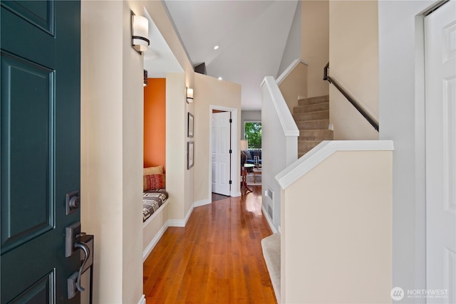 entrance foyer with lofted ceiling, stairway, light wood finished floors, and baseboards