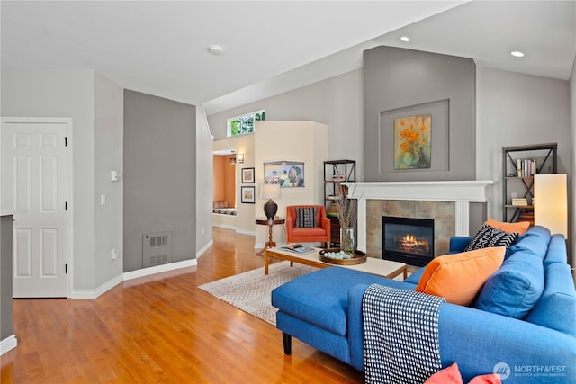 living area featuring baseboards, lofted ceiling, light wood-style floors, a fireplace, and recessed lighting