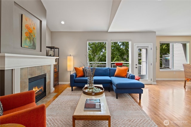 living room with baseboards, a fireplace, light wood-style flooring, and recessed lighting