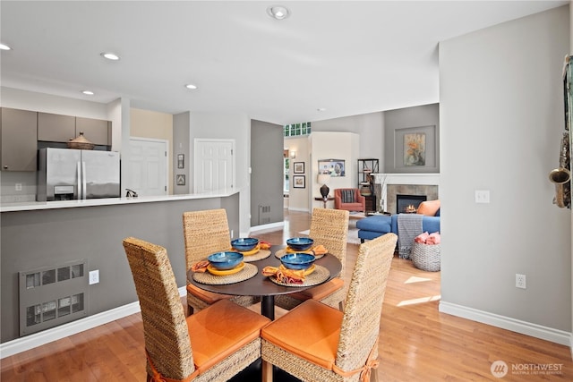 dining space with light wood-style flooring, baseboards, recessed lighting, and a fireplace