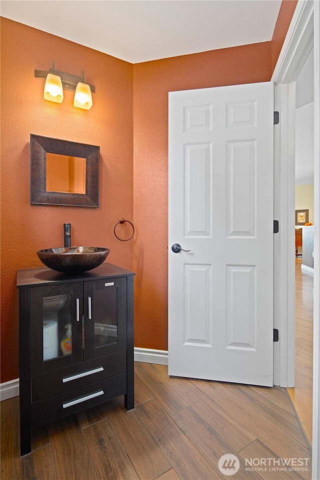 bathroom with wood finished floors, baseboards, and vanity