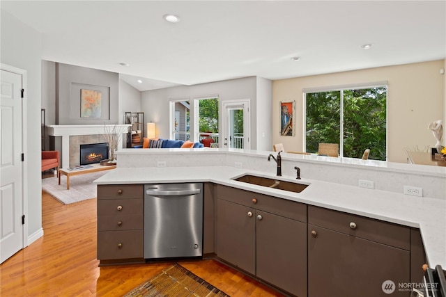 kitchen featuring stainless steel dishwasher, a sink, light wood-style floors, light countertops, and recessed lighting