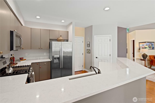 kitchen with appliances with stainless steel finishes, a sink, gray cabinets, light wood-style flooring, and recessed lighting