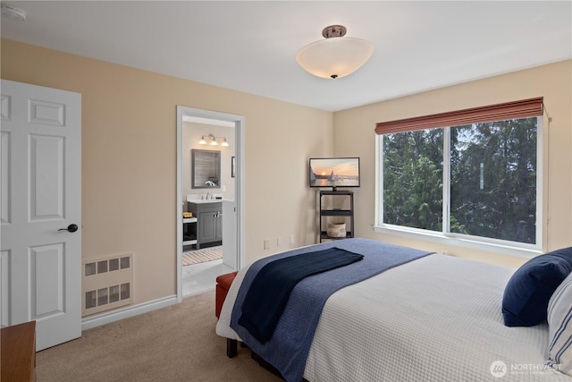bedroom featuring carpet, a sink, ensuite bath, and baseboards