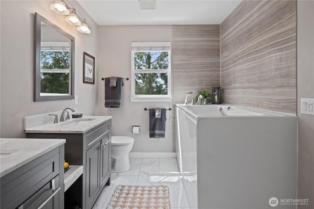 full bath featuring marble look tile flooring, vanity, toilet, a bath, and baseboards