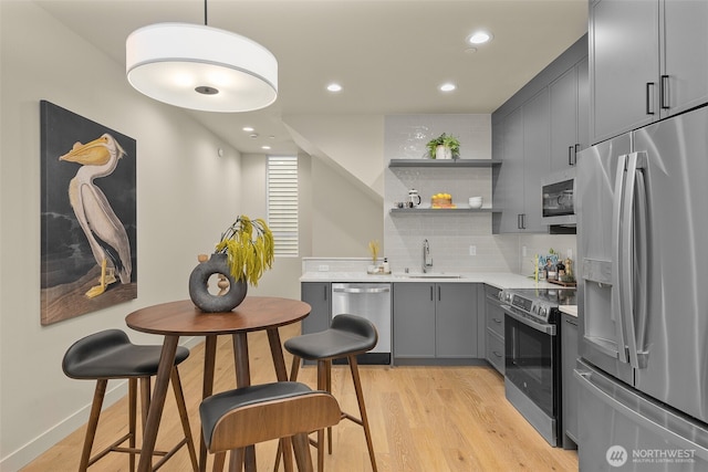 1106B 34th Ave, Seattle, WA 98122 - kitchen with appliances with stainless steel finishes, gray cabinetry, a sink, light wood-style flooring, and open shelves