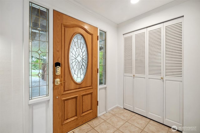 entryway with ornamental molding and light tile patterned flooring