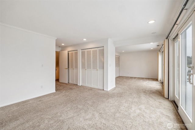 spare room featuring light colored carpet, recessed lighting, ornamental molding, and baseboards