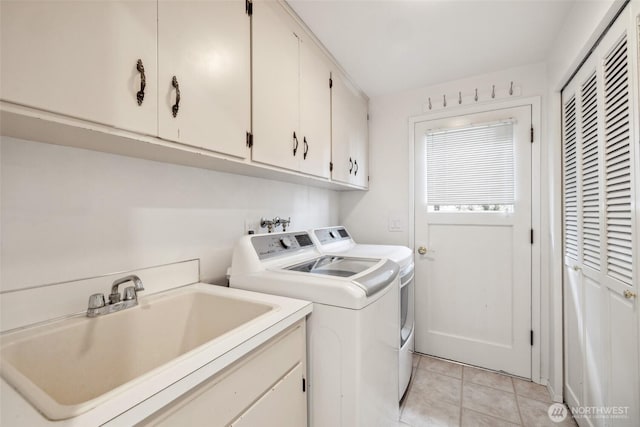 washroom featuring washing machine and dryer, cabinet space, and light tile patterned flooring