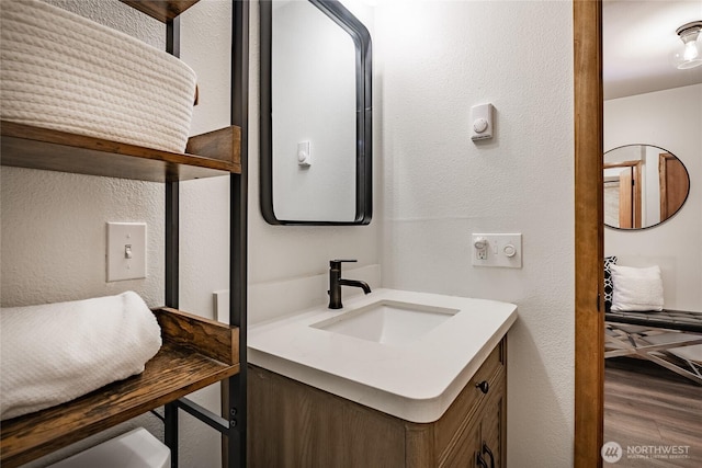 bathroom with a textured wall, wood finished floors, and vanity