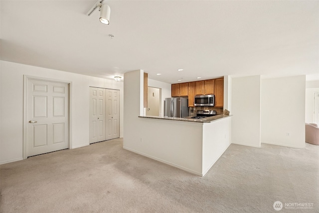 430 SW 156th St Unit 204, Burien, WA 98166 - kitchen featuring appliances with stainless steel finishes, light carpet, brown cabinets, baseboards, and tasteful backsplash