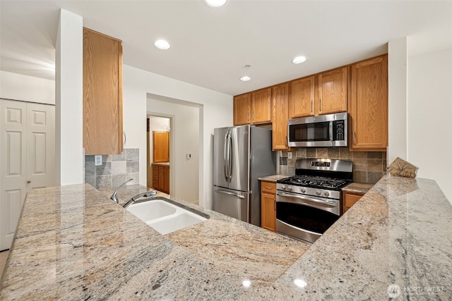 430 SW 156th St Unit 204, Burien, WA 98166 - kitchen featuring appliances with stainless steel finishes, a sink, light stone counters, decorative backsplash, and a peninsula