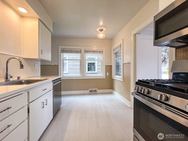 1915 Dexter Ave N, Seattle, WA 98109 - kitchen with stainless steel appliances, a sink, baseboards, and light countertops