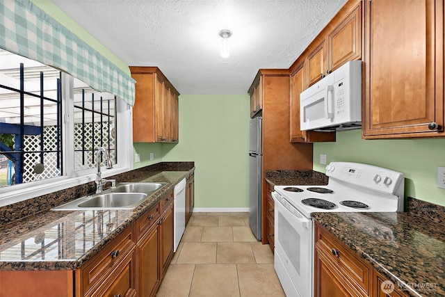 1811 S Sprague Ave, Tacoma, WA 98405 - kitchen with white appliances, a sink, brown cabinetry, dark stone countertops, and a textured ceiling