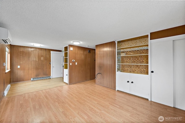 1811 S Sprague Ave, Tacoma, WA 98405 - unfurnished room featuring a baseboard heating unit, a wall unit AC, light wood-style flooring, wooden walls, and a textured ceiling