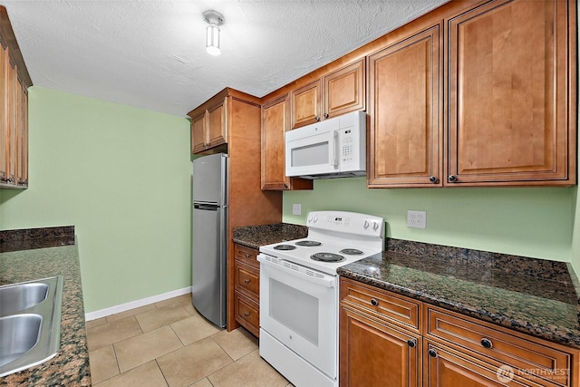 1811 S Sprague Ave, Tacoma, WA 98405 - kitchen featuring white appliances, brown cabinetry, a sink, baseboards, and light tile patterned floors