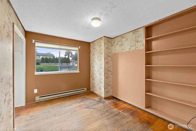 1811 S Sprague Ave, Tacoma, WA 98405 - unfurnished bedroom featuring a baseboard radiator, hardwood / wood-style flooring, a textured ceiling, and wallpapered walls