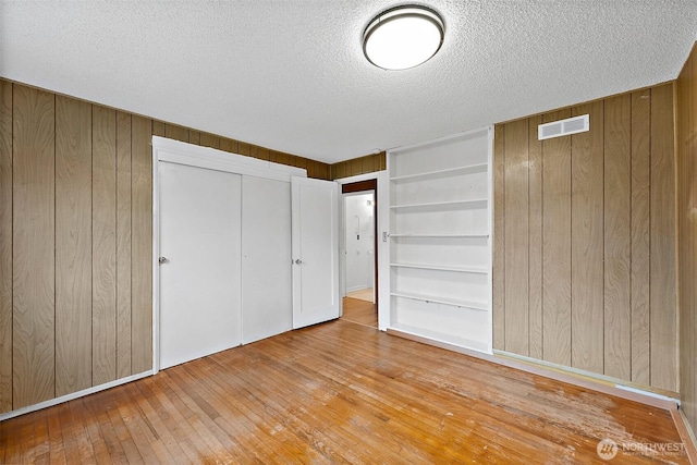 1811 S Sprague Ave, Tacoma, WA 98405 - unfurnished bedroom featuring wooden walls, hardwood / wood-style flooring, a textured ceiling, and a closet