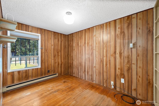 1811 S Sprague Ave, Tacoma, WA 98405 - empty room featuring a baseboard heating unit, hardwood / wood-style floors, a textured ceiling, and wood walls