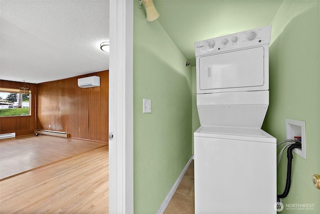 1811 S Sprague Ave, Tacoma, WA 98405 - clothes washing area with estacked washer and dryer, a baseboard heating unit, a wall mounted air conditioner, baseboards, and wooden walls
