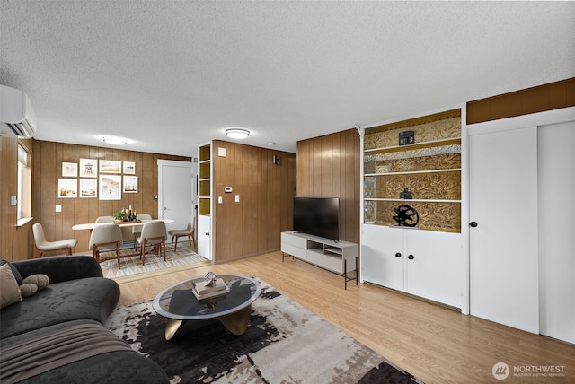 1811 S Sprague Ave, Tacoma, WA 98405 - living room with wood walls, an AC wall unit, a textured ceiling, and light wood-style flooring