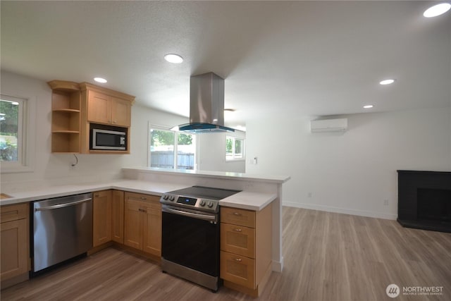 64 Queets St, Steilacoom, WA 98388 - kitchen featuring stainless steel appliances, island exhaust hood, a peninsula, a wall unit AC, and light wood-style flooring