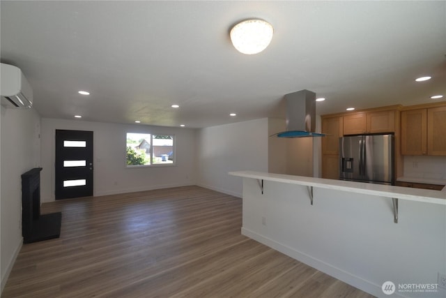 64 Queets St, Steilacoom, WA 98388 - kitchen featuring range hood, stainless steel fridge with ice dispenser, a kitchen bar, an AC wall unit, and light countertops