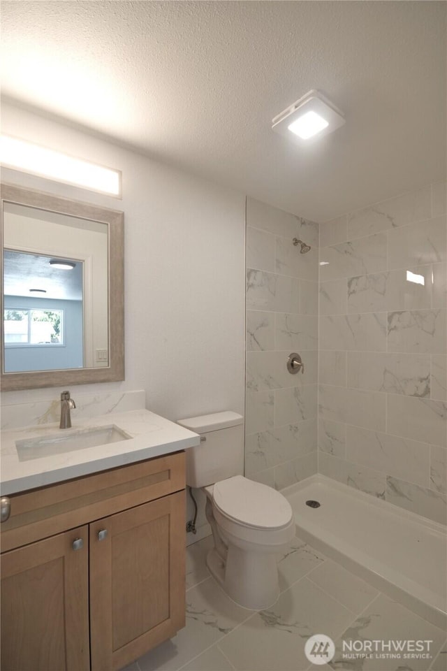 64 Queets St, Steilacoom, WA 98388 - full bath featuring marble look tiles, vanity, tiled shower, toilet, and a textured ceiling
