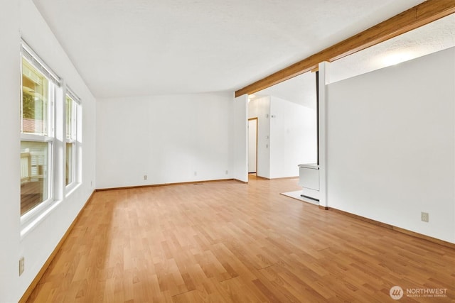 empty room featuring light wood-style floors, baseboards, and beam ceiling