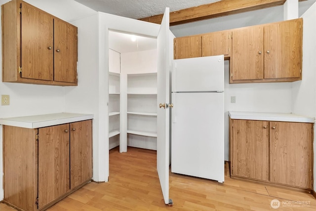 kitchen featuring freestanding refrigerator, light wood-style floors, and light countertops