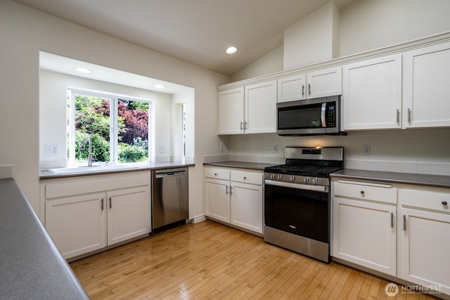 kitchen featuring stainless steel appliances, a sink, recessed lighting, white cabinetry, and light wood-style flooring
