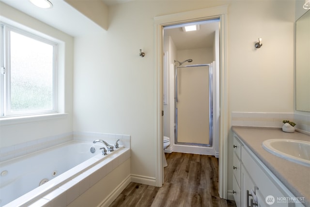 full bathroom with vanity, toilet, a shower stall, wood finished floors, and a jetted tub