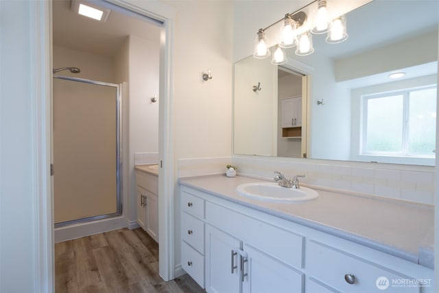 full bath with a stall shower, vanity, and wood finished floors