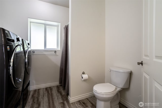 bathroom with washing machine and dryer, wood finished floors, toilet, and baseboards