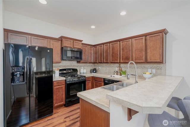 27815 NE 148th Ln, Duvall, WA 98019 - kitchen with black appliances, a peninsula, a breakfast bar, a sink, and light countertops