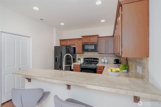 27815 NE 148th Ln, Duvall, WA 98019 - kitchen featuring black appliances, tasteful backsplash, a peninsula, a breakfast bar area, and brown cabinetry