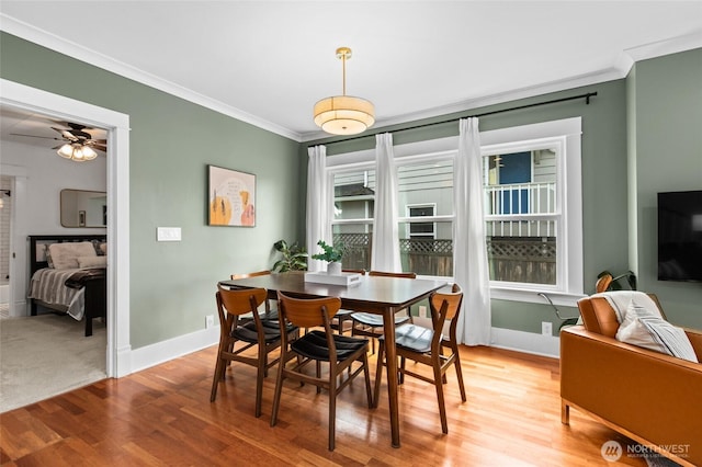 dining space featuring crown molding, light wood-style flooring, baseboards, and a ceiling fan