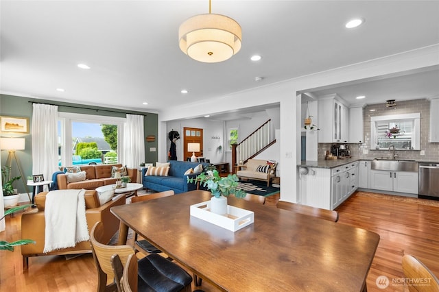 dining area with light wood-style flooring, recessed lighting, ornamental molding, and stairs