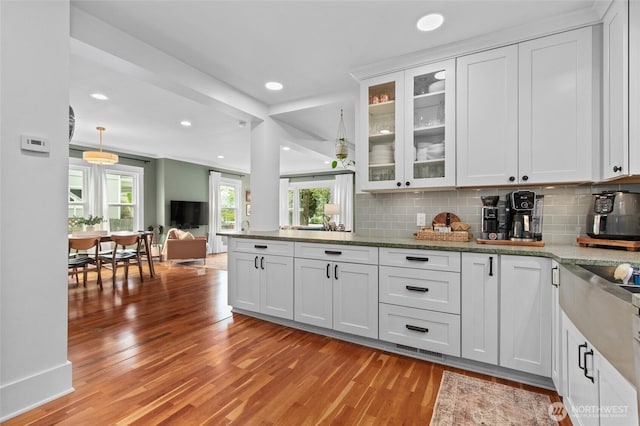 kitchen featuring light wood-style flooring, tasteful backsplash, recessed lighting, glass insert cabinets, and white cabinetry