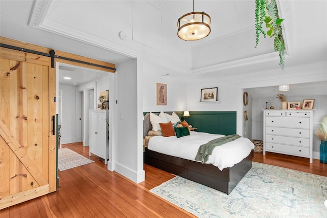 bedroom featuring wood finished floors, a barn door, and wainscoting