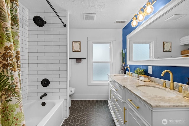 full bath with toilet, double vanity, a textured ceiling, baseboards, and tile patterned floors