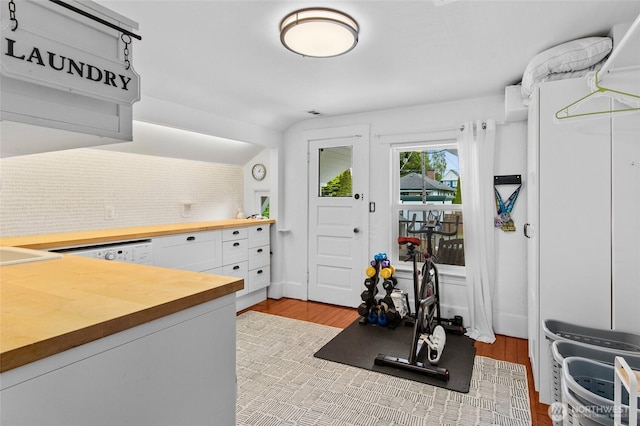 kitchen with butcher block countertops, tasteful backsplash, white cabinets, light wood-style floors, and lofted ceiling