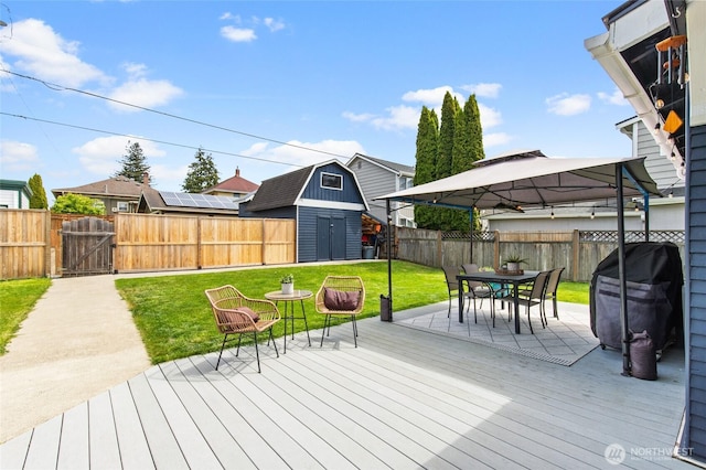 wooden terrace with a gazebo, a storage shed, outdoor dining area, an outdoor structure, and a gate